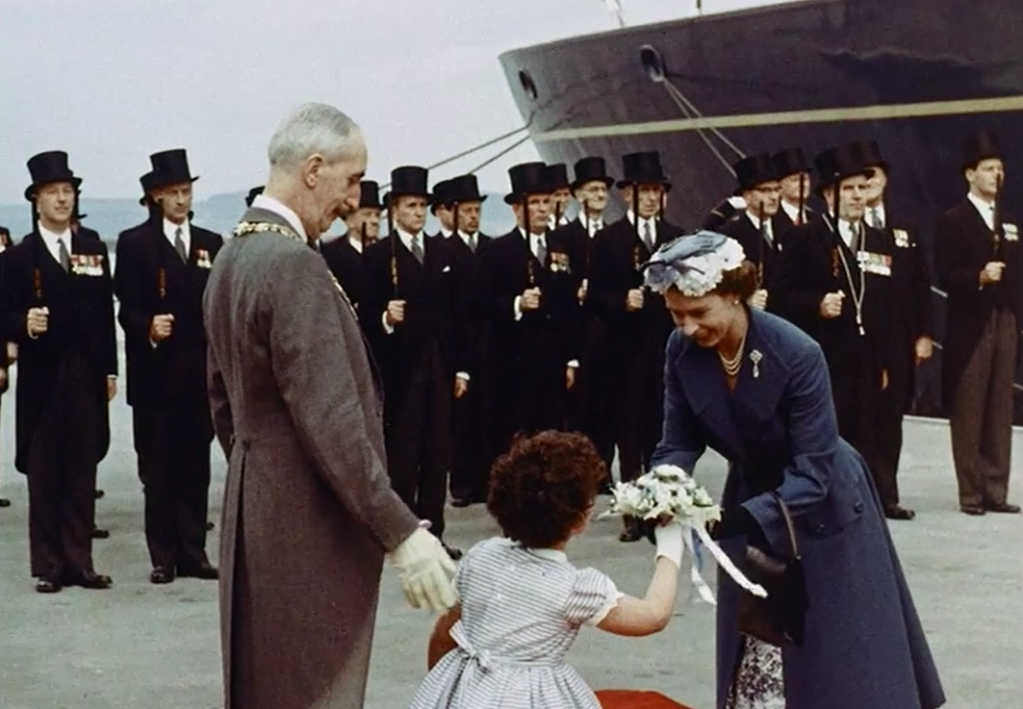 The High Constables of Leith form a guard of honour for the arrival of HM The Queen on arrival at Leith on the HMY Britannia in 1956. The girl presenting the bouquet was "6 year old Edwina Burness". Still from a film of the occasion held by the BFI.