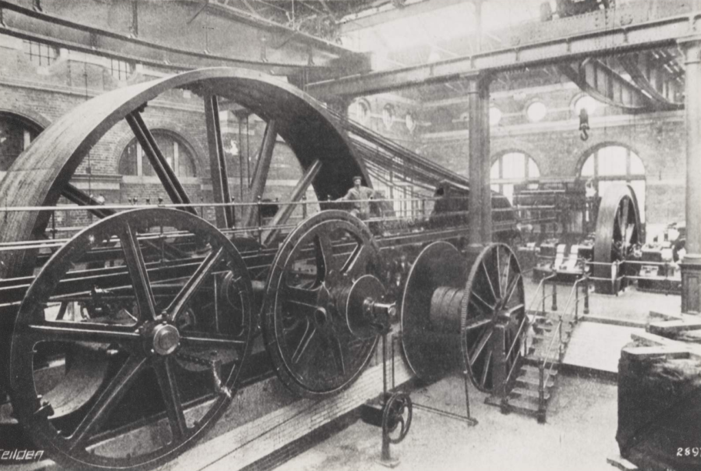 The winding house at Shrubhill. Notice the scale of the winding wheel compared to the man standing infront of it. © Edinburgh City Libraries